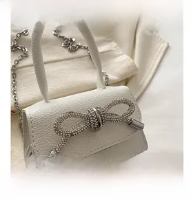 Détail du mini sac blanc en cuir litchi avec boucle de nœud étincelante en cristal