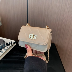 Mini beige quilted chain crossbody bag with gold twist lock shown in hand for size comparison