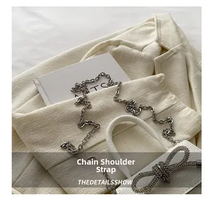 Détail du mini sac blanc en cuir avec nœud en strass brillant et bandoulière chaîne