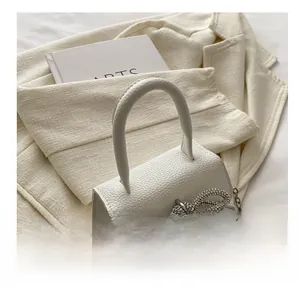Détail du sac à main blanc en cuir grainé avec un nœud étincelant en strass argentés