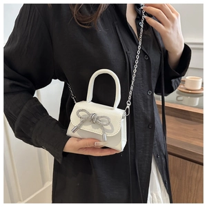 Détail du sac à main en cuir grainé avec nœud en strass et bandoulière en chaîne
