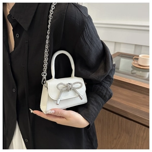 Détail du sac en cuir blanc avec nœud en strass et bandoulière chaîne argentée