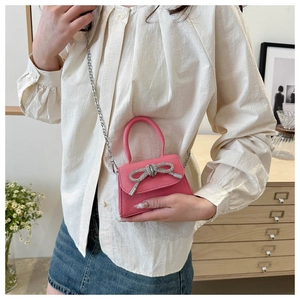 Détail du mini sac en cuir rose avec nœud en cristal brillant et bandoulière en chaîne