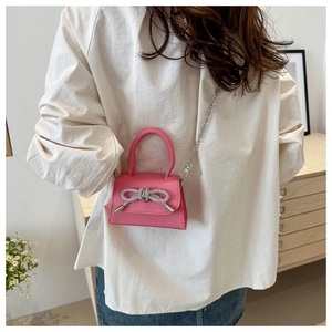 Détail du mini sac rose grainé avec nœud en strass brillant et bandoulière chaîne argent