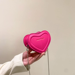 Magenta heart-shaped chain crossbody bag with gold logo shown held by hand