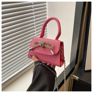 Gros plan d'un mini sac rose en cuir avec un nœud étincelant en strass et chaîne