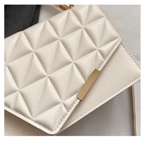 Gros plan sur un sac à bandoulière blanc cassé avec cuir matelassé et boucle dorée