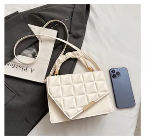 Détail du sac à main matelassé en similicuir crème avec barre dorée et poignée plissée