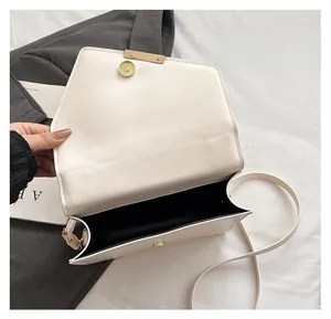 Détail du sac à bandoulière enveloppe blanc cassé avec garniture dorée et aimant