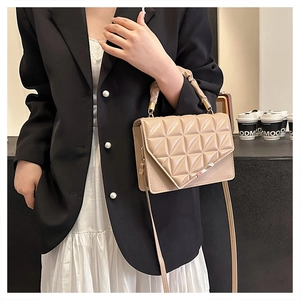 Détail du sac à main matelassé beige avec ferrures dorées et poignée plissée sur modèle