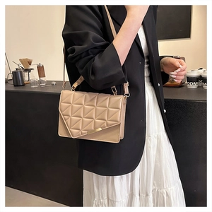 Détail du sac à bandoulière matelassé beige avec surpiqûres triangulaires et finitions dorées
