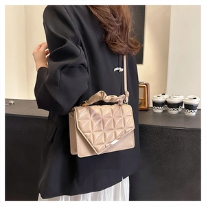 Détail du sac matelassé beige avec boucle dorée et poignée plissée élégante