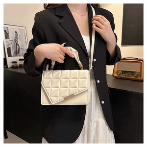 Détail du sac matelassé blanc cassé avec rabat triangulaire et bijoux dorés