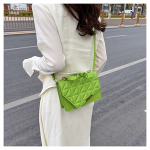 Gros plan d'un sac bandoulière vert vif avec texture matelassée et plis élégants