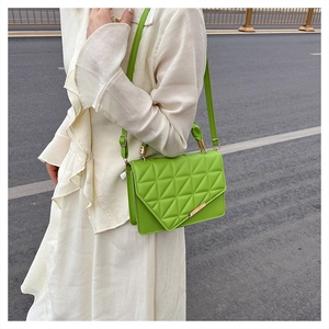Détail du sac bandoulière matelassé vert vif avec garniture dorée sur robe blanche