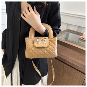 Macro detail of quilted beige PU leather bag with large silver metal bow buckle