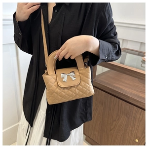 Detail of khaki quilted crossbody bag with silver bow fastener and delicate PU leather texture