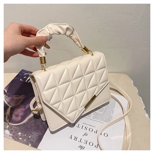 Gros plan du sac beige matelassé avec poignée plissée et anneaux en métal doré