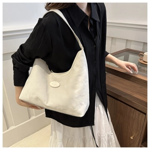 Close-up of cream PU leather hobo bag showing sleek oval logo and smooth shoulder strap