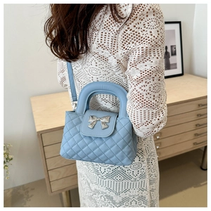 Detailed view of light blue quilted handbag featuring a silver bow metal accessory