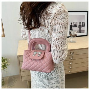 Detailed view of pink quilted handbag with silver bow accent on lace dress outfit