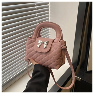 Detailed view of pink quilted handbag featuring a silver bow hardware and PU leather texture