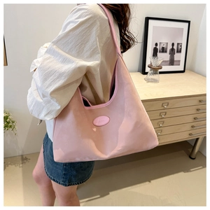 Close-up of pink nylon tote bag with brand logo patch and smooth leather trim finish