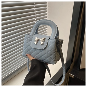 Detail of light blue quilted tote bag with silver bow hardware and top handles