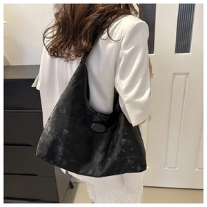 Detail of vintage black soft leather tote bag with wide strap and embossed brand logo
