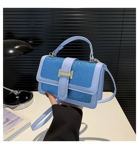 Detail of elegant small square bag showing purple leather and blue glitter patchwork