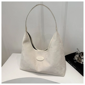 Detail of the minimalist white soft leather hobo bag showing the brand tag and strap