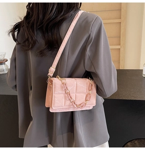 Detailed shot of pink quilted crossbody bag with chunky resin chain and leather strap