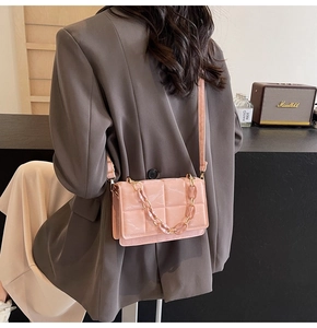 Détail d'un sac bandoulière rose matelassé avec chaîne et fine sangle en cuir