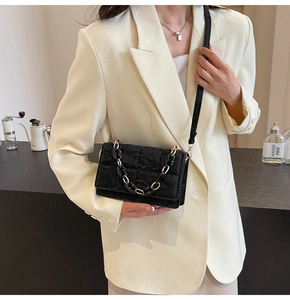 Detail of black quilted crossbody bag with stylish gold and black chain strap
