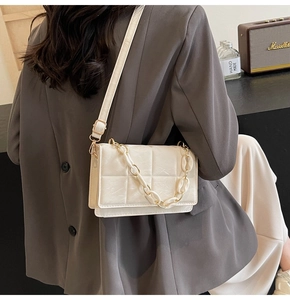 Detail of cream quilted crossbody bag with matching leather strap and chain
