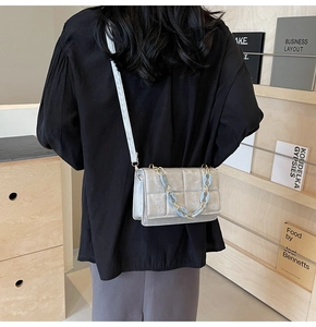 Détail du sac bandoulière matelassé gris argenté avec chaîne élégante en résine bleue