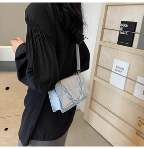 Détail du sac matelassé bleu clair montrant la grosse chaîne et le design en accordéon
