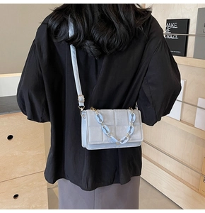 Detailed back view of light blue quilted crossbody bag with stylish chain decor