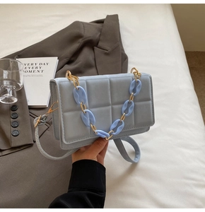 Close-up of light blue quilted square bag with textured stitching and chunky chain strap