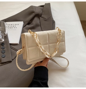 Detail of beige quilted shoulder bag with golden chain and acrylic handle strap