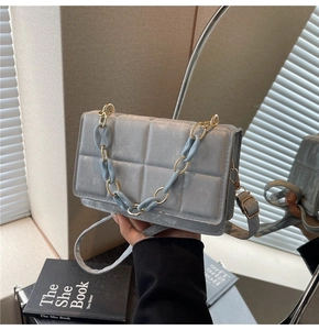 Detail of light blue quilted square handbag with gold and acrylic chain decor