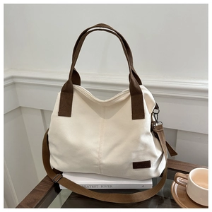 Close-up of canvas tote bag showing the fashion label and brown adjustable strap details