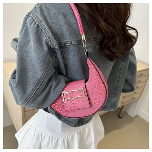 Close-up of pink faux-crocodile texture on a crescent shoulder bag with gold chain details