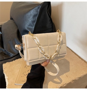 Close-up of cream quilted square bag with gold metal and white resin chunky chain detail