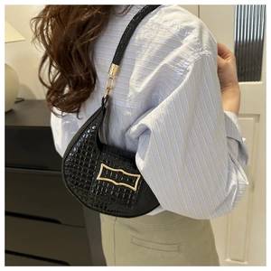 Detail showing black crocodile texture and gold buckle on the stylish shoulder bag