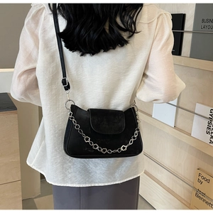 Detail of black crossbody bag featuring a unique silver floral chain and matte finish