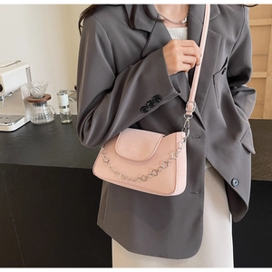 Détail du sac bandoulière rose avec chaîne florale argentée décorative et texture douce