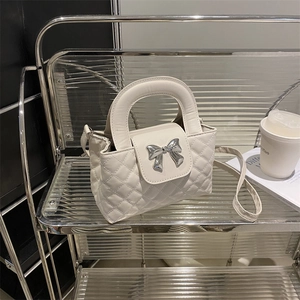 White quilted handbag with silver bow detail and top handle for modern urban style