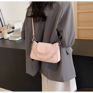 Détail du sac à bandoulière rose clair avec chaîne florale argentée et logo de marque