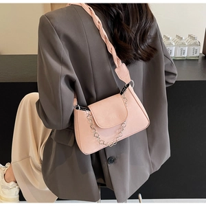 Détail du sac à épaule rose avec bandoulière tressée et chaîne à fleurs argentées